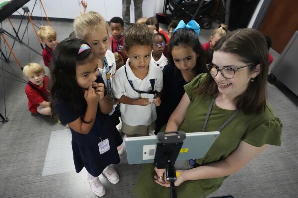 Art and technology teacher Jenny O'Sullivan, right, shows students a video they made, Monday, April 15, 2024, at A.D. Henderson School in Boca Raton, Fla. While many teachers nationally complain their districts dictate textbooks and course work, the South Florida school's administrators allow their staff high levels of classroom creativity...and it works. (AP Photo/Wilfredo Lee)