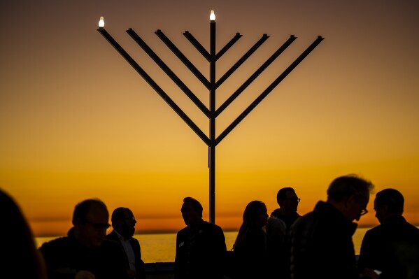 FILE - People gather around the 10-foot menorah during the "Hanukkah on the Pier" event at the end of the San Clemente pier hosted by Chabad of San Clemente in San Clemente, Calif., Sunday, Dec. 18, 2022. On eight consecutive nightfalls, Jews gather with family and friends to light one additional candle in the menorah candelabra. They do so to commemorate the rededication of the Temple in Jerusalem in the 2nd century BC, after a small group of Jewish fighters liberated it from occupying foreign forces. (Leonard Ortiz/The Orange County Register via 麻豆传媒app, File)