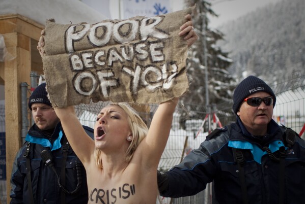 FILE - A topless Ukrainian protester is arrested by Swiss police after climbing up a fence at the entrance to the center where the World Economic Forum is held in Davos, Switzerland, Jan. 28, 2012. The activists are from the group Femen, which had become popular in Ukraine for staging small, half-naked protests against a range of issues including oppression of political opposition. (AP Photo/Anja Niedringhaus, File)