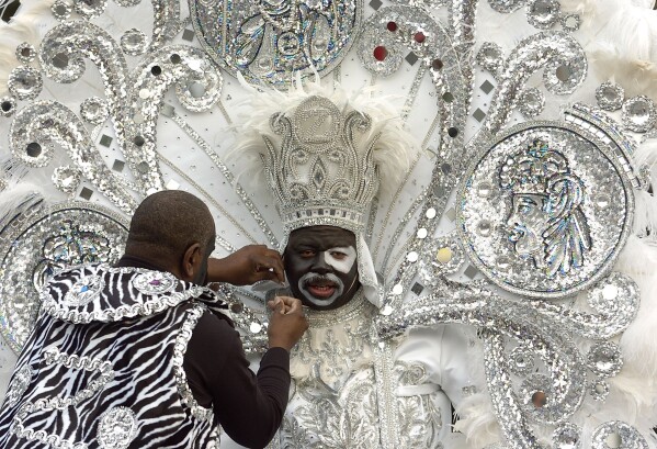 Zulu King Isaac Spencer Wheeler gets help with his head piece from Vincent Stripling left, at the start of the Zulu parade on Mardi Gras in New Orleans, Feb. 8, 2005. (AP Photo/Alex Brandon, file)