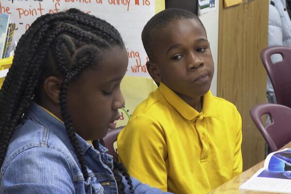 Third-graders Michael Crowder, center, and Malaysia Strickland, left, work together on a reading comprehension project at Boyd Elementary School in Atlanta, on Dec. 15, 2022. Until the end of third grade, students generally receive guidance from teachers to perfect their literacy. After that, students are expected to read more challenging texts in all of their subjects and to improve reading skills on their own. (AP Photo/Sharon Johnson)