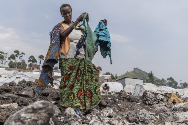 2024年6月6日，星期四，60岁的安妮·玛丽·尼库泽（Anne-Marie Nikuze）与她的子女和孙子住在刚果民主共和国戈马附近的穆甘加难民营，她正在收集财物。刚果东部一个流离失所营地发生火灾，烧毁了约50个临时帐篷，数十个家庭无家可归。周三下午，省会戈马附近的穆贡加流离失所者营地的帐篷被烧成灰烬。（美联社照片/Moses Sawasawa）