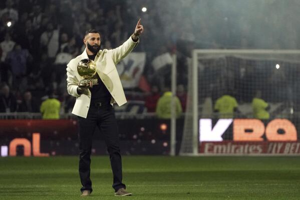 Former Lyon player Karim Benzema holds his 2022 Ballon d'Or trophy during the French League One soccer match between Lyon and Nice, in Decines, outside Lyon, central France, Friday, Nov. 11, 2022. (AP Photo/Laurent Cipriani)