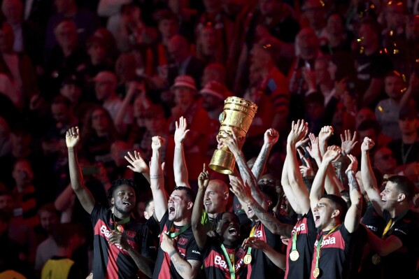 Leverkusen's team celebrates with the trophy after winning the German Soccer Cup final match between 1. FC Kaiserslautern and Bayer Leverkusen at the Olympic Stadium in Berlin, Germany, Saturday, May 25, 2024. (Soeren Stache/dpa via AP)