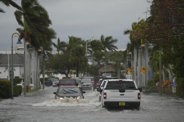 Drivers navigate a flooded street following the passage of Hurricane Nicole, Thursday, Nov. 10, 2022, in Fort Pierce, Fla. (AP Photo/Rebecca Blackwell)