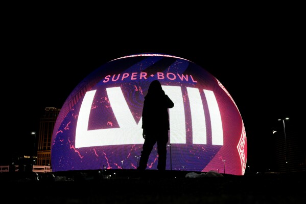 A person is silhouetted against a Super Bowl 58 graphic playing on the Sphere Thursday, Feb. 8, 2024 in Las Vegas. The Kansas City Chiefs will play the NFL football game against the San Francisco 49ers Sunday in Las Vegas. (APPhoto/Charlie Riedel)