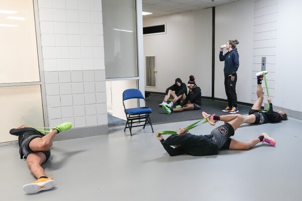 CORRECTS TO SOUTH CAROLINA PLAYERS, NOT UCLA AS ORIGINALLY SENT - South Carolina players stretch in the hallway of the MVP Arena before practice during the NCAA Tournament in Albany, N.Y., Saturday, March 30, 2024. The second year of the super regional format for the women's NCAA Tournament presented some logistical challenges for arena staff and the teams involved. The locker rooms were reserved for teams with practices and games. Those coming in for shootarounds came dressed and occasionally stretched in corridors while waiting for the court to become available.(AP Photo/Mary Altaffer)