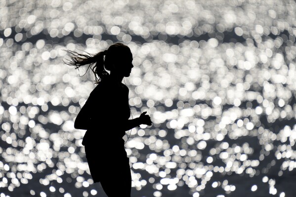FILE - A runner makes her way along the path at Gray's Lake Park, Friday, April 14, 2023, in Des Moines, Iowa. The killing of a 22-year-old nursing student has once again put the spotlight on dangers faced by female athletes who practice sports alone. (AP Photo/Charlie Neibergall, File)