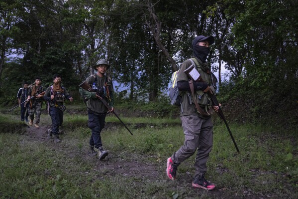 FILE- Armed tribal Kuki community members patrol near a de facto front-line dissecting the area into two ethnic zones in Churachandpur, in Manipur, India, June 20, 2023. Police say at least two people have been killed in an exchange of gunfire with security forces in a troubled northeastern state. The shootout took place in the east Pallel village area in Manipur state on Friday. (AP Photo/Altaf Qadri, File)