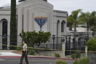 FILE - In this Sunday, April 28, 2019 file photo, a San Diego county sheriff's deputy stands in front of the Chabad of Poway synagogue, in Poway, Calif. A California judge on Wednesday, July 7, 2021 decided victims of the 2019 synagogue shooting near San Diego that killed one worshiper and wounded three can sue the manufacturer of the semiautomatic rifle and the gun shop that sold it to the teenage gunman, according to a newspaper report.(AP Photo/Denis Poroy, File)