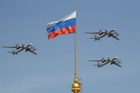 FILE - In this file photo taken on Friday, May 4, 2018, Russian Tu-95 strategic bombers fly past the Russian flag on the Kremlin complex during a rehearsal for the Victory Day military parade in Moscow, Russia.  South Korean air force jets fired 360 rounds of warning shots after a Russian military plane briefly violated South Korea's airspace twice on Tuesday, Seoul officials said, in the first such incident between the two countries. (AP Photo/Pavel Golovkin, File)