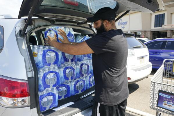 Rajwinder Singh, a gas station/convenience store owner, pats into place the 15 cases of drinking water he purchased from a Kroger grocery store into his vehicle, Tuesday, Aug. 30, 2022, in Jackson, Miss. Parts of Jackson were without running water Tuesday because recent flooding worsened problems in one of two water-treatment plants as part of the city's response to longstanding water system problems. The state Health Department put Mississippi's capital city under a boil-water notice in late July. (AP Photo/Rogelio V. Solis)