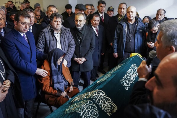 Nuriye Cihan, bottom, mother of Tuncer Cihan who was killed on an attack to a Catholic church, mourns next to Istanbul Mayor Ekrem Imamoglu, left, during a funeral ceremony in Istanbul, Turkey, Monday, Jan. 29, 2024. The Islamic State group has claimed responsibility for an attack on a Roman Catholic church in Istanbul during a Sunday Mass that killed one person. (Sercan Ozkurnazli/Dia Images via AP)