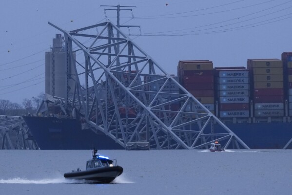 A container ship rests against wreckage of the Francis Scott Key Bridge as night falls on Tuesday, March 26, 2024, as seen from Sparrows Point, Md. The ship rammed into the major bridge in Baltimore early Tuesday, causing it to collapse in a matter of seconds and creating a terrifying scene as several vehicles plunged into the chilly river below. (AP Photo/Matt Rourke)