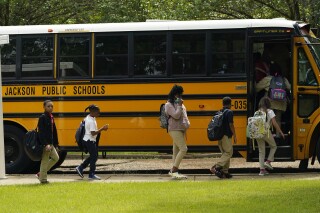 FILE - Spann Elementary School students board a school bus following a full day of in-school learning, Sept. 6, 2022, in Jackson, Miss. After the COVID-19 pandemic disrupted schools around the country and led to more children missing classes, the number of students who were chronically absent in Mississippi declined during the most recent school year, according to data released, Tuesday, Sept. 26, 2023, by the state's education department. (AP Photo/Rogelio V. Solis, File)