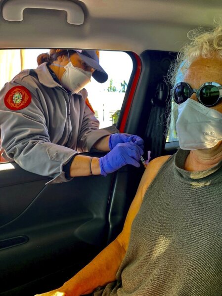 This undated photo provided by Tami Katz–Freiman, of Miami, shows her getting a COVID-19 vaccine. Katz-Freiman, 65, got her second dose, and plans to watch the Miami Film Festival virtually Sunday, March 7, 2021, at the home of unvaccinated friends. All will wear masks. The Biden administration said Friday, March 5, it’s focused on getting the guidance for those fully vaccinated right and accommodating emerging science. (Tami Katz–Freiman via AP)