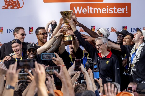 The German basketball team celebrates with fans after their arrival in Frankfurt, Germany, Tuesday, Sept. 12, 2023. Germany beat Serbia in the basketball world championships final in Manila last Sunday. Word in the background reads 'World Champions' (AP Photo/Michael Probst)