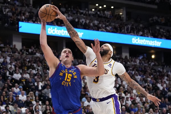 Los Angeles Lakers forward Anthony Davis (3) gets a hand on the ball against Denver Nuggets center Nikola Jokic (15) during the second half in Game 1 of an NBA basketball first-round playoff series Saturday, April 20, 2024, in Denver. (AP Photo/Jack Dempsey)