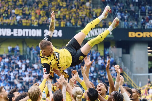 Dortmund's Marcus Reus is thrown into the air after the Bundesliga soccer match between Borussia Dortmund and SV Darmstadt 98 at the Signal Iduna Park in Dortmund, Germany, Saturday May 18, 2024. This is the last match of Marco Reus with Borussia Dortmund. (Bernd Thissen/dpa via AP)