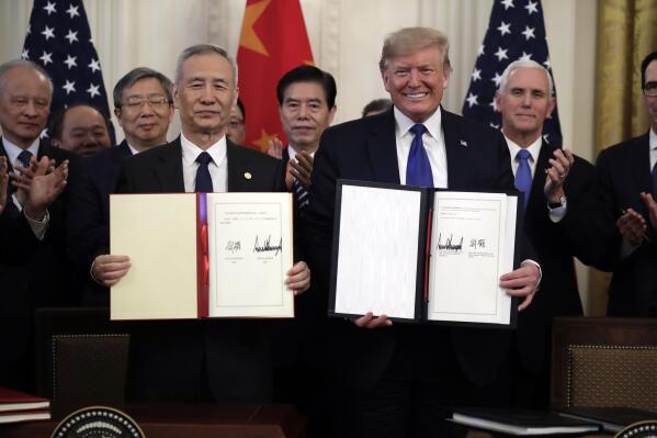 FILE - In this Jan. 15, 2020, file photo President Donald Trump holds a trade agreement with Chinese Vice Premier Liu He, in the East Room of the White House in Washington. Trump spent four years upending seven decades of American trade policy. He started a trade war with China, slammed America’s closest allies by taxing their steel and aluminum and terrified Big Business by threatening to take a wrecking ball to $1.4 trillion in annual trade with Mexico and Canada.
 Trump’s legacy on trade is likely to linger, regardless whether Joe Biden replaces him in the White House in January 2021.(AP Photo/Evan Vucci)