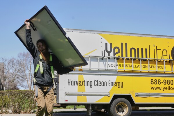 Theodore Tanczuk, of solar installer YellowLite, carries a panel from his truck to the roof of a home in Lakewood, Ohio, Wednesday, April 16, 2025. (AP Photo/Sue Ogrocki)