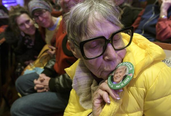 Odelia Rogers, 81, kisses a button with a photo of former President Donald Trump before Trump speaks at a campaign event Monday, March 13, 2023, in Davenport, Iowa. (AP Photo/Ron Johnson)
