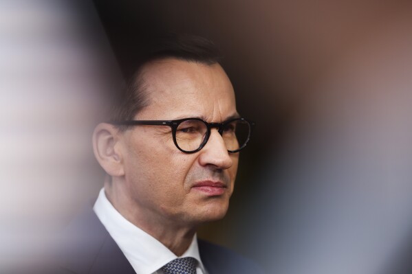 FILE - Poland's Prime Minister Mateusz Morawiecki talks to journalists as he arrives for the third EU-CELAC summit in Brussels, Belgium, Tuesday, July 18, 2023. Poland’s ruling party wants to ask voters in a referendum if they support accepting “thousands of illegal immigrants from the Middle East and Africa” as part of a European Union relocation plan. The prime minister announced the referendum question Sunday, Aug. 13, 2023, in a new video published on social media as his conservative party seeks to stave off a challenge from the political opposition. (AP Photo/Geert Vanden Wijngaert, File)