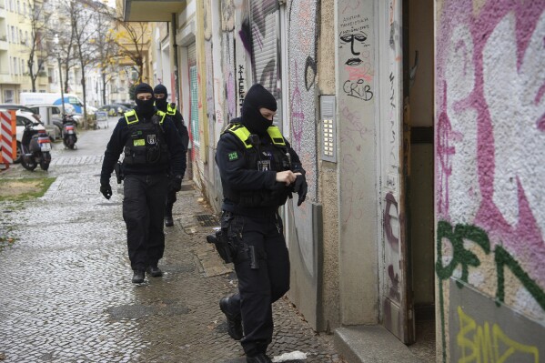 Police officers walk to the entrance of a building during a raid in Berlin, Germany, Thursday, Nov. 23, 2023. Around 280 police officers have searched several properties in eight German states in connection with investigations into the far-right Reich Citizens scene which rejects the legitimacy of Germany’s postwar constitution and has similarities to the Sovereign Citizens and QAnon movements in the United States. (Paul Zinken/dpa via AP)