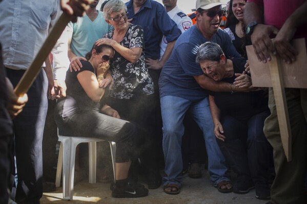 FILE - Gila Tragerman, center left, mother of four-year-old Israeli boy, Daniel Tragerman, sits next to his grave during his funeral in a cemetery located next to the Israeli community of Yevul, near the Israel-Gaza border, Sunday, Aug. 24, 2014. Daniel was killed when a mortar shell hit two cars in the parking lot of Nahal Oz, a small farming community near Gaza. (AP Photo/Oren Ziv)