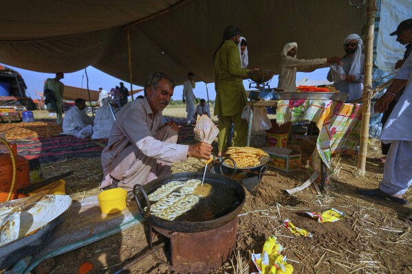 A vendor prepares traditional sweets called 'Jalebi' at his stall at the venue of a traditional bull race competition, in Malal, a village of Attock district, in Pakistan, Thursday, May 15, 2025. (AP Photo/Anjum Naveed)