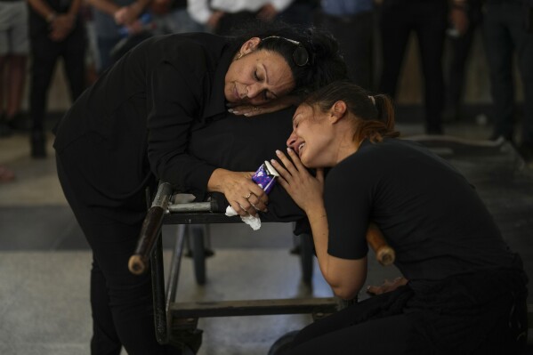 Mourners grieve beside the body of Mapal Adam during her funeral in Tel Aviv, Israel, Wednesday, Oct. 11, 2023. Adam was killed by Hamas militants on Saturday as they carried out an unprecedented, multi-front attack that killed over 1,300 Israelis. (AP Photo/Francisco Seco)