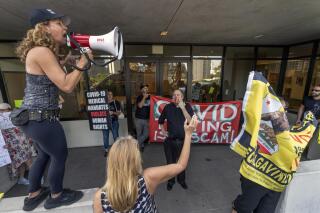 Anti-vaccine mandate protesters and supporters of the California recall election rally outside the front doors of the Los Angeles Unified School District, LAUSD headquarters in Los Angeles Thursday Sept. 9, 2021. The Los Angeles board of education voted Thursday to require students 12 and older to be vaccinated against the coronavirus to attend in-person classes in the nation's second-largest school district. (AP Photo/Damian Dovarganes)
