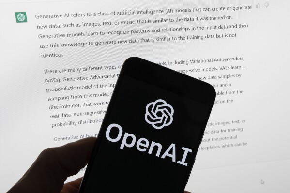 FILE - The OpenAI logo is seen on a mobile phone in front of a computer screen displaying output from ChatGPT, March 21, 2023, in Boston. Several news organizations, writers and photographers groups are seeking regulations to govern the fast-moving artificial intelligence technology that threatens upheavals for their businesses. In an open letter sent on Wednesday, Aug. 9, 2023, outlined priorities for setting rules on the technology, which is developing faster than regulators can keep up with. (AP Photo/Michael Dwyer, File)