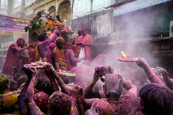 Hindu devotees with offerings make way to reach the car which carried the deity Shri Krishna during the Holi festival in Kolkata, India, Sunday, March 5, 2023. Millions of Indians on Wednesday celebrated the ''Holi" festival, dancing to the beat of drums and smearing each other with green, yellow and red colors and exchanging sweets in homes, parks and streets. Free from mask and other COVID-19 restrictions after two years, they also drenched each other with colored water. (AP Photo/Bikas Das)