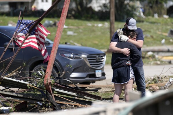 Local residents hug in front of their tornado damaged home, Wednesday, May 22, 2024, in Greenfield, Iowa. (AP Photo/Charlie Neibergall)