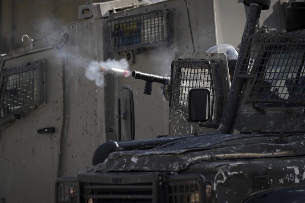 An Israeli officer fires tear gas at Palestinians during a military operation in the Balata refugee camp, West Bank, Tuesday, Nov. 21, 2023. (AP Photo/Majdi Mohammed)