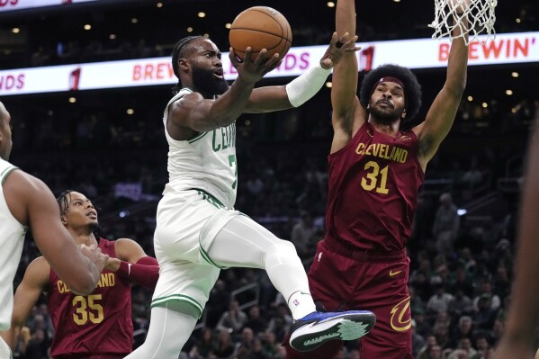 Boston Celtics guard Jaylen Brown, left, drives to the basket against Cleveland Cavaliers center Jarrett Allen (31) during the first half of an NBA basketball game, Tuesday, Dec. 12, 2023, in Boston. (AP Photo/Charles Krupa)