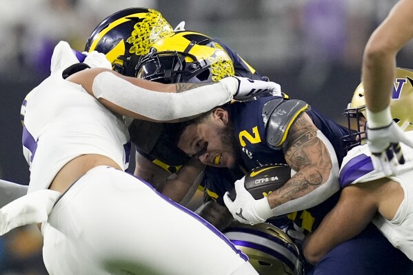 Michigan running back Blake Corum is tackled by Washington during the first half of the national championship NCAA College Football Playoff game Monday, Jan. 8, 2024, in Houston. (AP Photo/Eric Gay)
