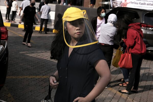 A woman wears a face shield as a precaution against the new coronavirus outbreak serve customers at a McDonald's restaurant in Jakarta, Indonesia, Sunday, May 10, 2020. (AP Photo/Dita Alangkara)