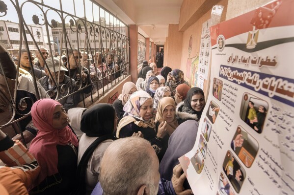 FILE - Egyptian voters crowd to cast their votes for the presidential elections at a polling station, in Cairo, Egypt, Sunday, Dec. 10, 2023. A leading human rights group dismissed on Thursday, Feb. 9, 2024, the conviction of a prominent Egyptian political activist as an act of retaliation for the latter’s decision to challenge President Abdel Fattah el-Sissi in last year’s presidential poll. On Tuesday, a Cairo misdemeanor court had sentenced former presidential hopeful Ahmed Altantawy along with 22 of his aides, including his campaign's manager, to one year in prison on grounds of disseminating unauthorized endorsement forms for his candidacy. Arabic at right reads, 