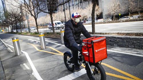 FILE - In this March 16, 2020 file photo, a delivery worker rides his bicycle along a path on the West Side Highway in New York. New York City was ordered Friday, July 7, 2023, to temporarily delay new minimum pay standards for food delivery workers after being sued by Uber Eats, DoorDash and Grubhub. (AP Photo/John Minchillo, File)