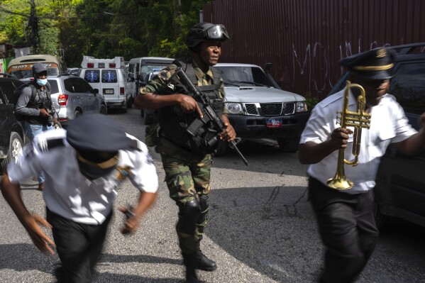 Police escort musicians arriving for the swearing-in ceremony of a transitional council tasked with selecting a new prime minister and cabinet at the Prime Minister's office in Port-au-Prince, Haiti, Thursday, April 25, 2024. (AP Photo/Ramon Espinosa)