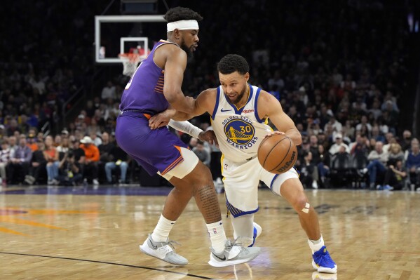 Golden State Warriors guard Stephen Curry (30) drives past Phoenix Suns guard Jordan Goodwin during the first half of an NBA basketball game, Tuesday, Dec. 12, 2023, in Phoenix. (AP Photo/Rick Scuteri)