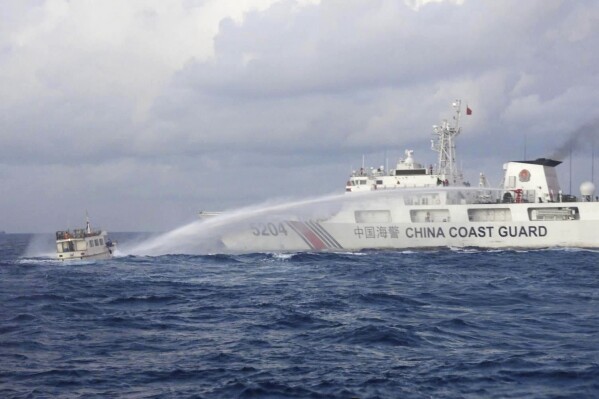 In this handout photo provided by the Philippine Coast Guard, a Chinese Coast Guard ship uses water cannons on Philippine navy-operated supply boat M/L Kalayaan as it approaches Second Thomas Shoal, locally known as Ayungin Shoal, in the disputed South China Sea on Sunday Dec. 10, 2023. The Chinese coast guard targeted Philippine vessels with water cannon blasts Sunday and rammed one of them, causing damage and endangering Filipino crew members off a disputed shoal in the South China Sea, just a day after similar hostilities at another contested shoal, Philippine officials said. (Philippine Coast Guard via AP)