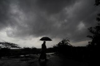 FILE - A villager holds an umbrella as dark clouds loom over Balasore district in Odisha, India, Tuesday, May 25, 2021, ahead of a powerful storm barreling toward the eastern coast. When it comes to measuring global warming, it’s not just the heat, it’s the humidity that matters in dangerous climate extremes, according to a study released on Monday, Jan. 31, 2022, in the Proceedings of the National Academy of Sciences in the U.S. (AP Photo/File)