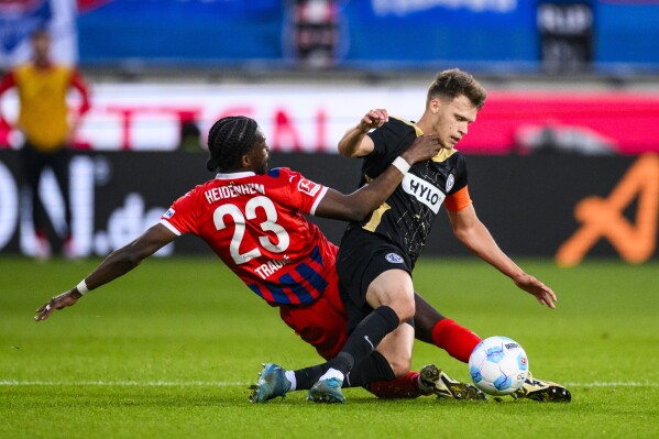 Heidenheim's Omar Traore, left, and Elversberg's Robin Fellhauer battle for the ball during a Bundesliga relegation playoff first leg soccer match between FC Heidenheim and SV Elversberg, Thursday, May 22, 2025, in Heidenheim, Germany. (Tom Weller/dpa via AP)