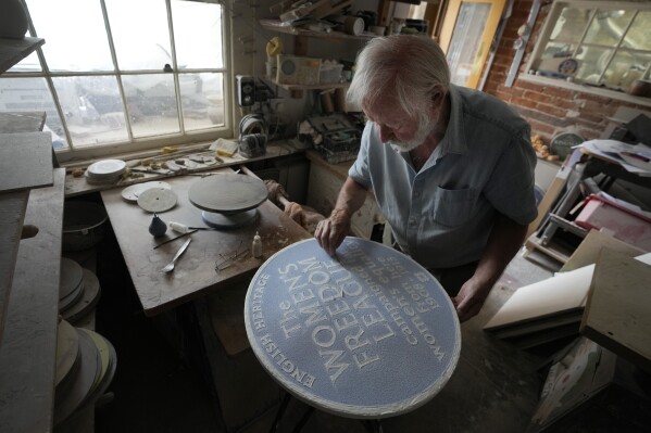Ned Heywood fettling the glaze on the clay plaque during the making of an English Heritage Blue Plaque, at Heritage Ceramics, The Workshop Gallery in Chepstow, Wales Wednesday, Sept. 6, 2023. English Heritage is preparing to unveil its 1,000th blue plaque, the famous discs that dot the walls of buildings throughout London, marking the places where scientists, artists, politicians and activists have made history. The charity is working to broaden the program to include more women, people from minority ethnic backgrounds and community groups so that it better reflects the diversity of the capital. (AP Photo/Kirsty Wigglesworth)