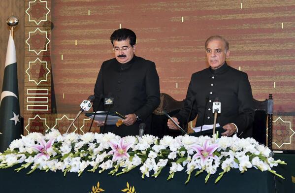In this photo released by Press Information Department, acting President of Pakistan Sadiq Sanjrani, left, administers the oath of office to newly elected Pakistani Prime Minister Shahbaz Sharif during a ceremony at Presidential Palace, in Islamabad, Pakistan, Monday, April 11, 2022. Pakistan's parliament elected opposition lawmaker Sharif as the new prime minister Monday, following a week of political turmoil that led to the weekend ouster of Premier Imran Khan. (Press Information Department via AP)