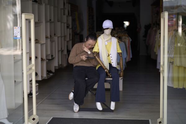 A vendor sit at her shop, during a major power outage in Barcelona, Spain, Monday, April 28, 2025. (AP Photo/Emilio Morenatti)