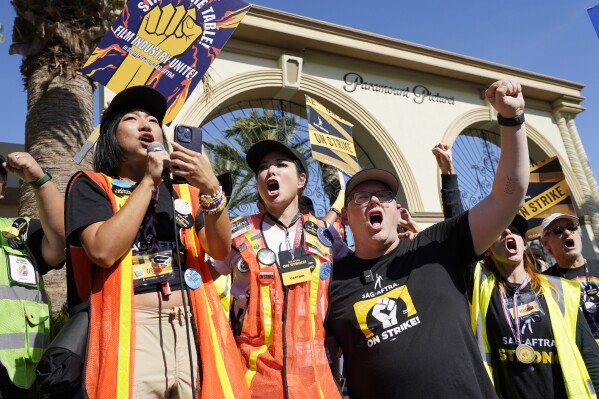 FILE - SAG-AFTRA captains Iris Liu, left, and Miki Yamashita, center, and SAG-AFTRA chief negotiator Duncan Crabtree-Ireland lead a cheer for striking actors outside Paramount Pictures studio, Nov. 3, 2023, in Los Angeles. While negotiators with SAG-AFTRA have made gains in bargaining over wages and job safety in their video game contract, leaders say talks have stalled over a key issue: protections over the use of artificial intelligence. (AP Photo/Chris Pizzello, File)